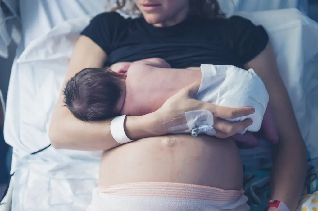 A woman holding her baby in the arms of another woman.