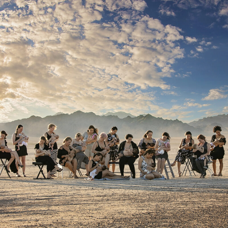 A group of people sitting on chairs in the sand.