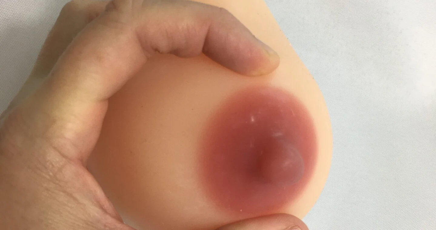 A person's hand demonstrating how to express milk or colostrum from a breast