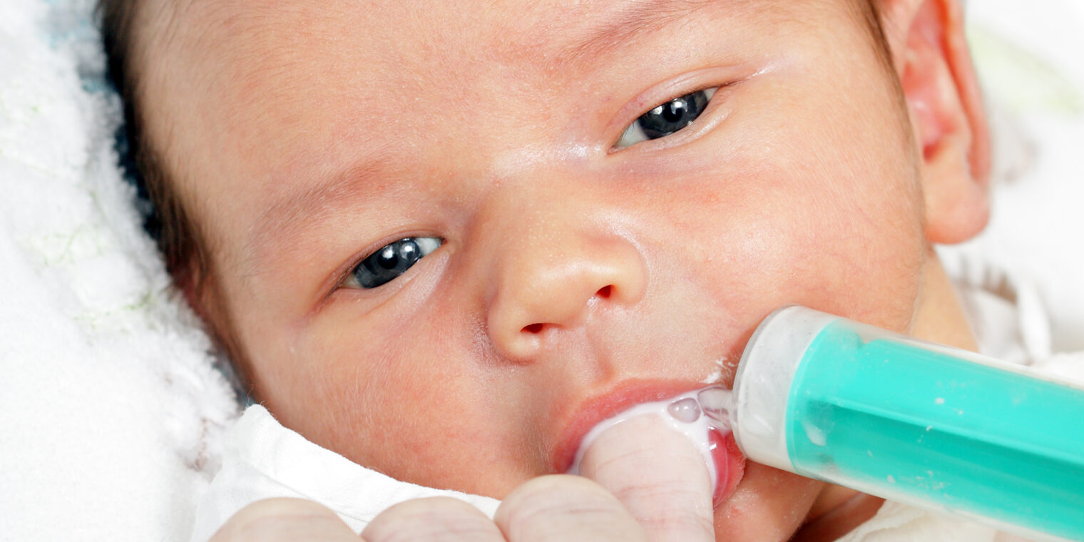 A baby is holding a toothbrush in its mouth.