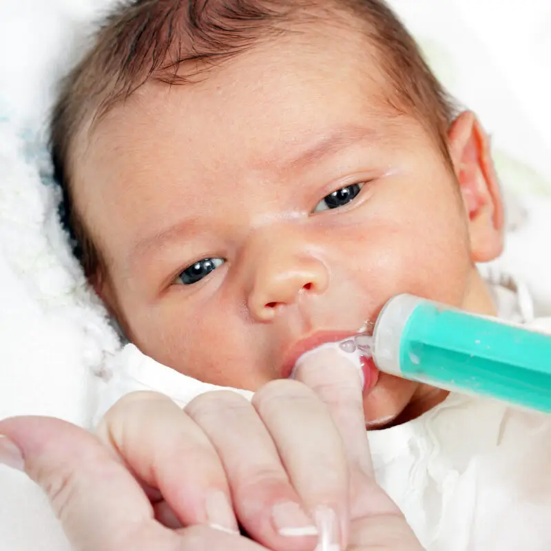 A baby is holding a toothbrush in its mouth.