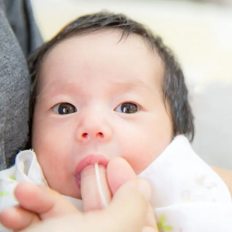 A baby being held by its mother while she is holding the pacifier.