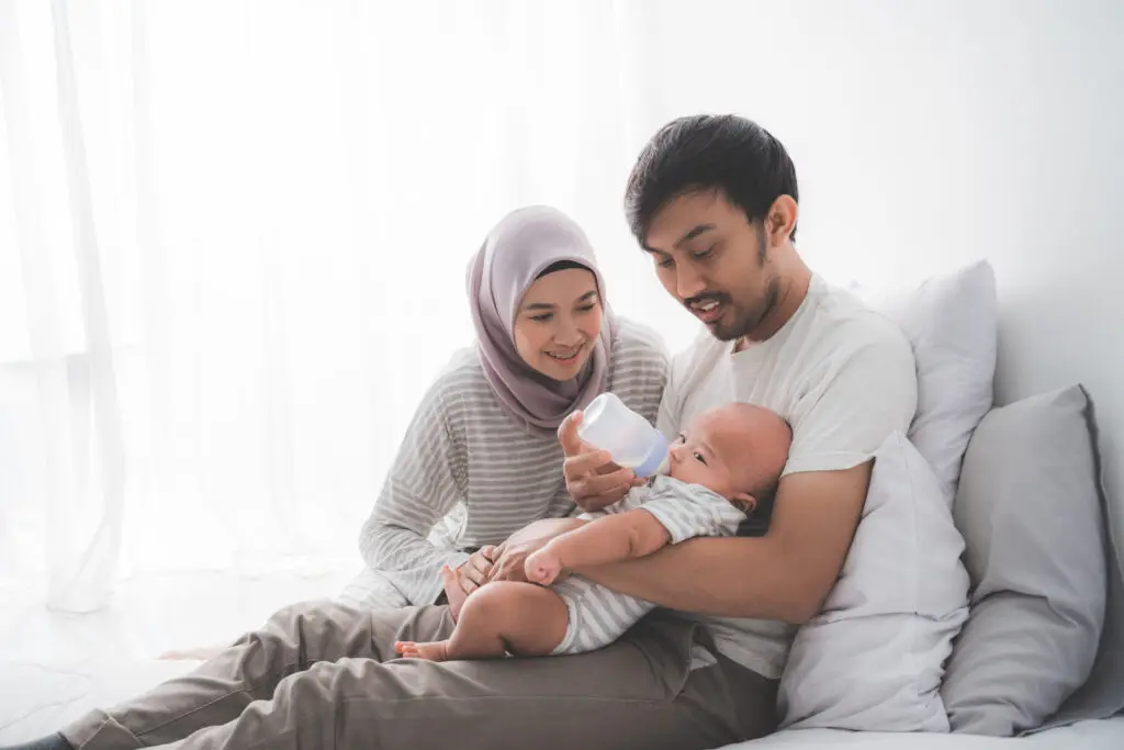 A man and woman holding a baby while sitting on the ground.