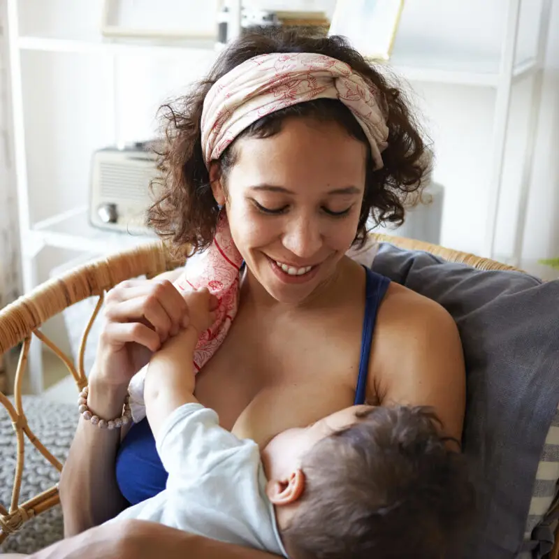 A woman is holding her baby in the arms of another woman.