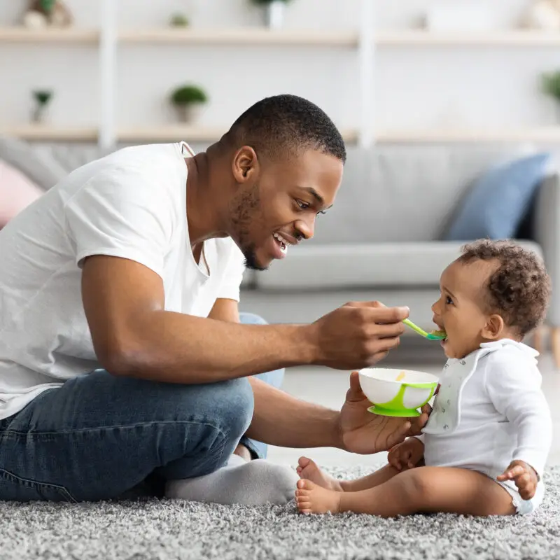 A man feeding a baby with a spoon.