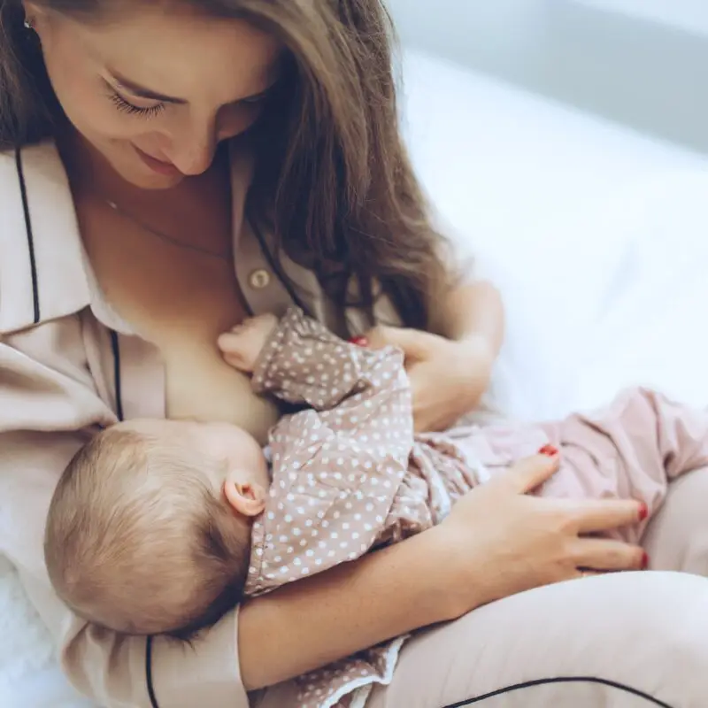 A woman holding a baby and wearing pajamas.