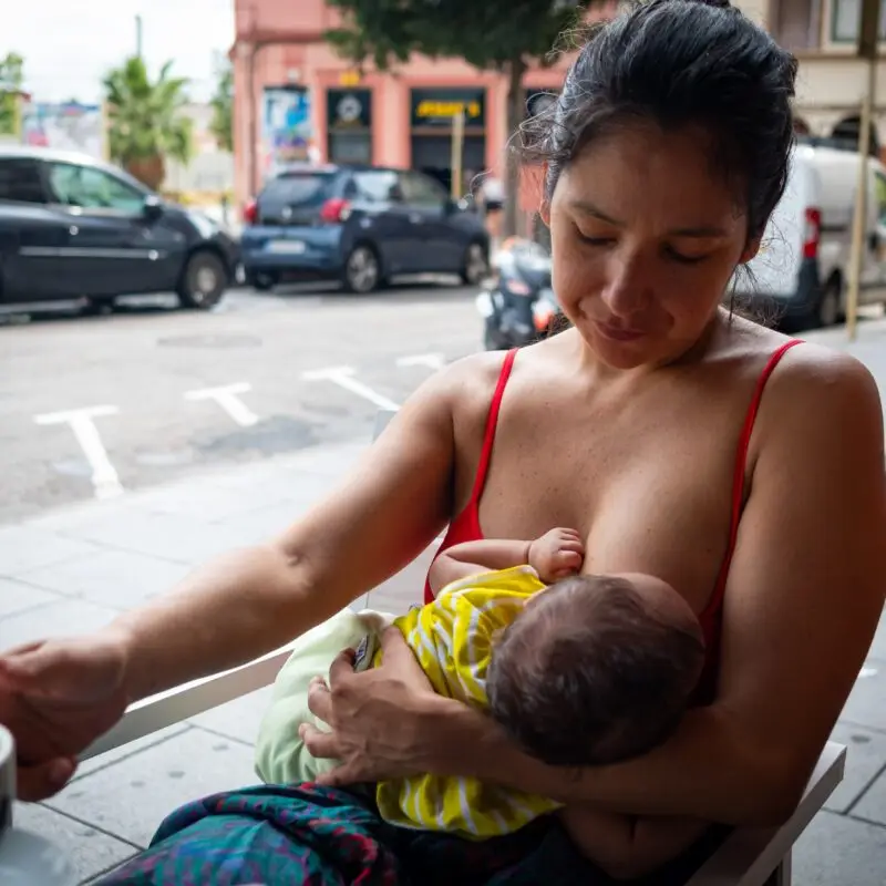 A woman is breastfeeding her baby in the street.
