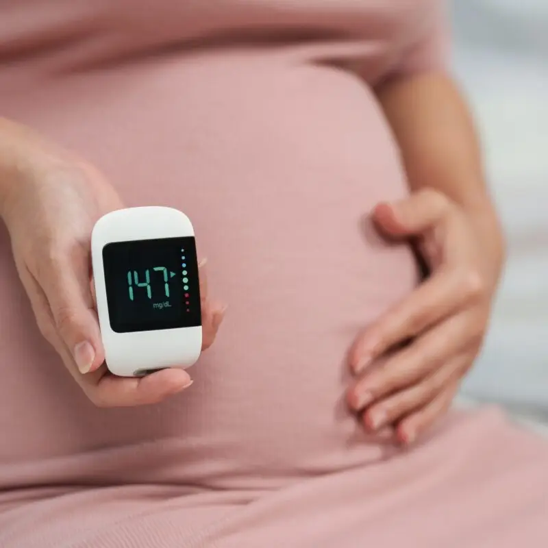 A pregnant woman holding her stomach and showing the time.