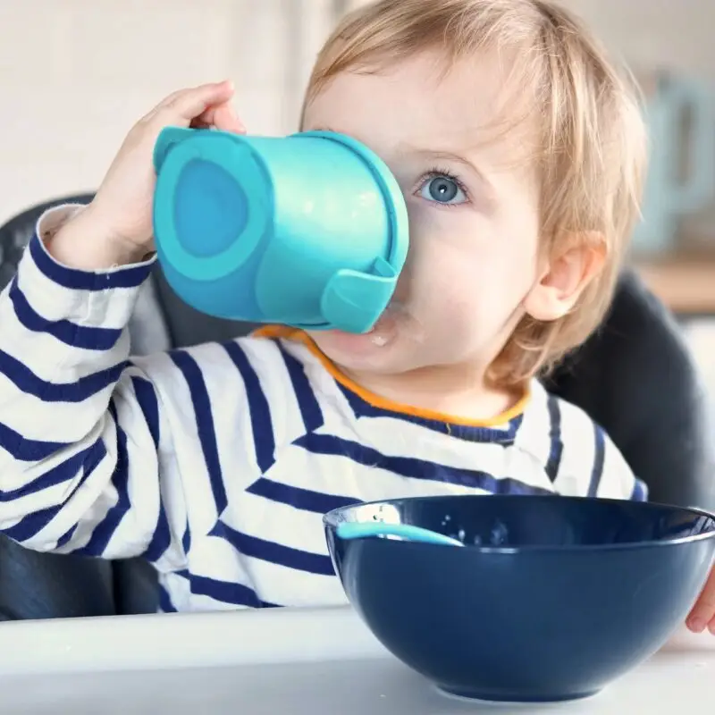 A child drinking from a cup at the table