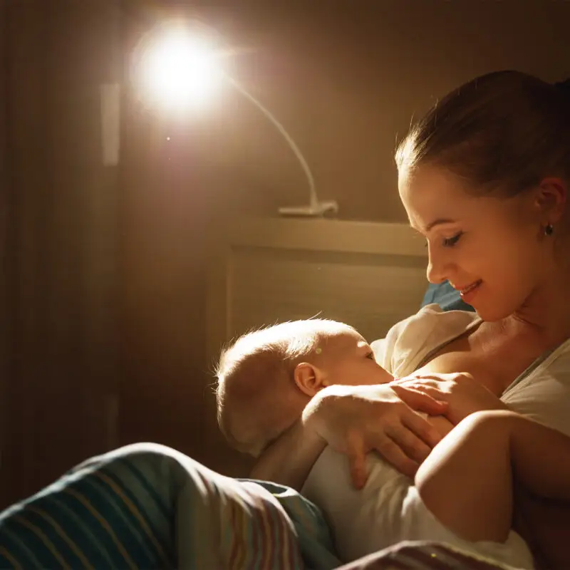 A woman is feeding her baby in the dark.