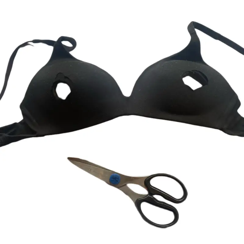 A pair of bras and scissors are laying on the floor.