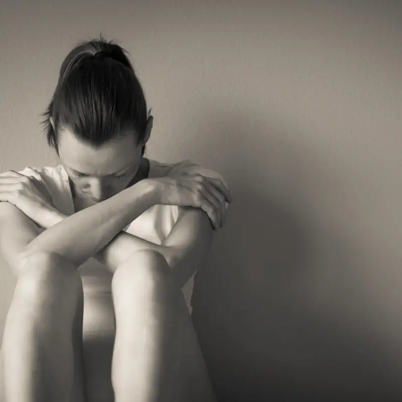 A woman sitting on the ground with her arms crossed.