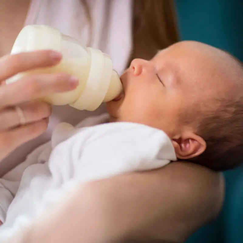 A woman feeding a baby with a bottle.