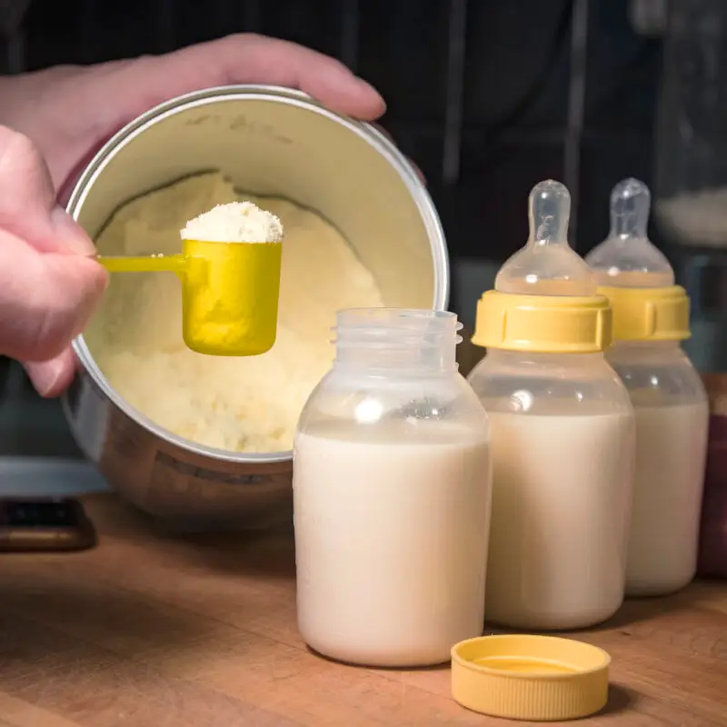 A person pouring milk into baby bottles