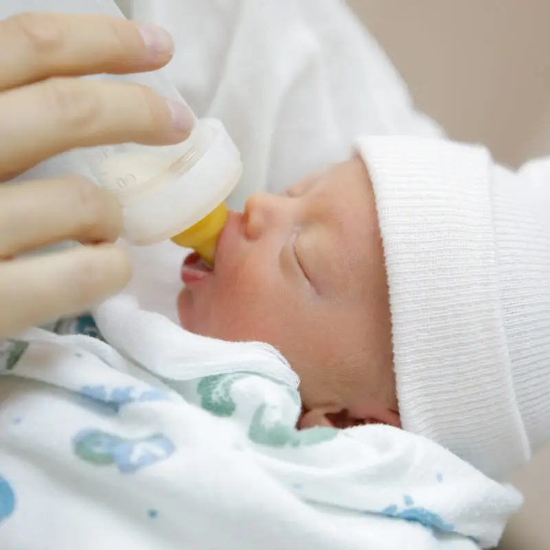 A baby is being fed a bottle by someone