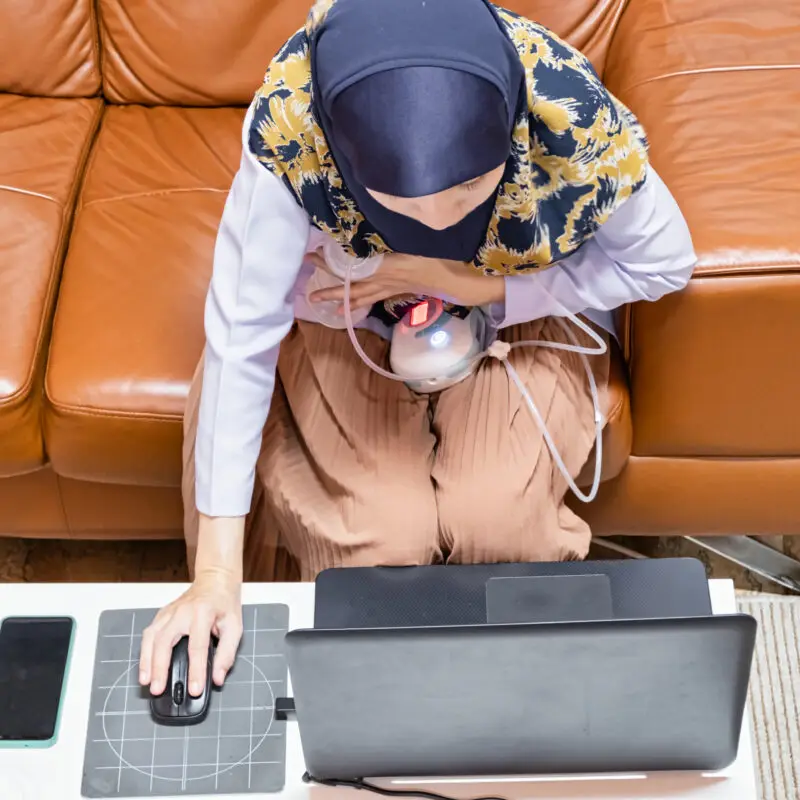 A woman sitting on top of a brown couch.