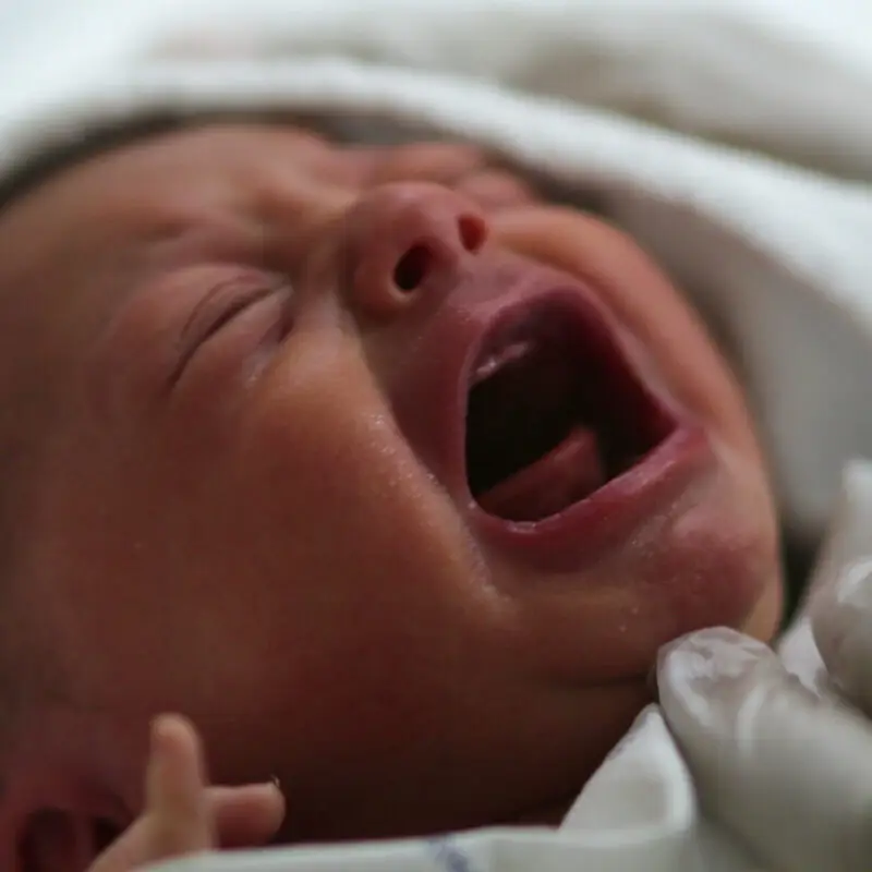 A baby is crying while laying in bed.