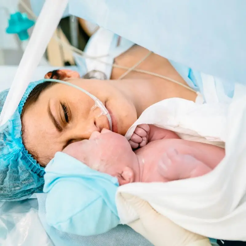 A woman in blue scrubs holding a baby.