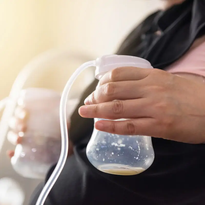 A person holding a bottle of breast milk